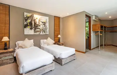 a bedroom with two beds and a painting on the wall at Villa Yoga by Villa Finder in Seminyak