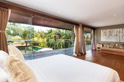 a bedroom with a white bed and a large window at Villa Yoga by Villa Finder in Seminyak