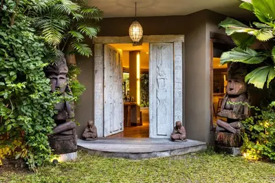 a front door of a house with two large statues at Villa Yoga by Villa Finder in Seminyak