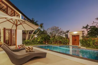 a house with a swimming pool and an umbrella at Villa Tramonto By Le Cielo in Canggu