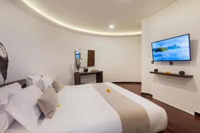 a bedroom with a white bed with a tv on the wall at Villa Tramonto By Le Cielo in Canggu