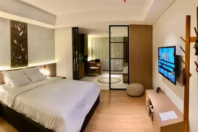 a bedroom with a bed and a desk and a television at Cozy Minimalist Apartment Lavaya N511 in Nusa Dua