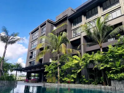 a building with palm trees and a swimming pool at Cozy Minimalist Apartment Lavaya N511 in Nusa Dua