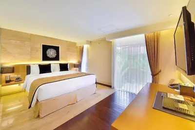 a bedroom with a bed and a desk and a television at de Vins Sky Hotel Seminyak in Seminyak