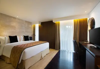 a hotel room with a bed and a flat screen tv at de Vins Sky Hotel Seminyak in Seminyak