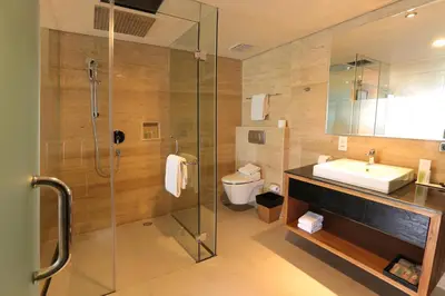a bathroom with a shower and a sink and a toilet at de Vins Sky Hotel Seminyak in Seminyak