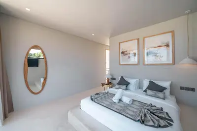 a white bedroom with a large bed and a mirror at Berawa Breeze - Chic 4BR Beachside Oasis with Sauna in Canggu