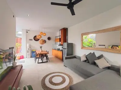 a living room with a gray couch and a kitchen at Cosy Haven 2 BR Villa in Umalas in Canggu
