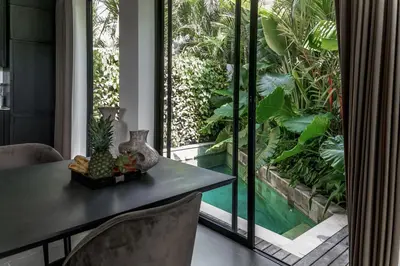 a dining room with a table and a large window at Premier Umalas Villas in Seminyak
