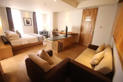 a living room with a couch and a bed and a television at Liberta Hotel Jimbaran in Jimbaran