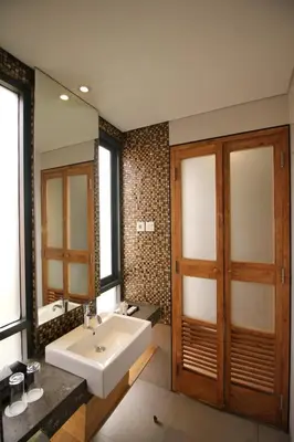 a bathroom with a sink and a large mirror at Liberta Hotel Jimbaran in Jimbaran