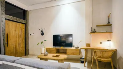 a living room with a couch and a tv on a wall at Alaya Homes B - Stylish Japandi Loft Suite in Seminyak in Seminyak