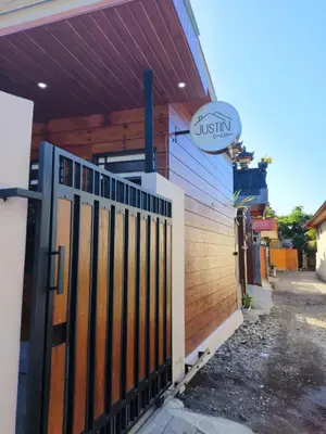 a wooden fence in front of a building at Justin Guest House in Jimbaran