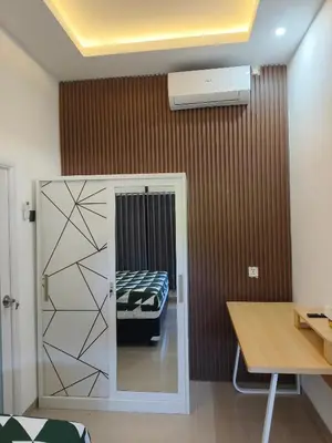 a room with a bed and a desk and a table at Justin Guest House in Jimbaran