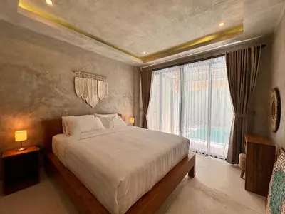 a bedroom with a bed and a large window at Villa de Mer Bali in Legian