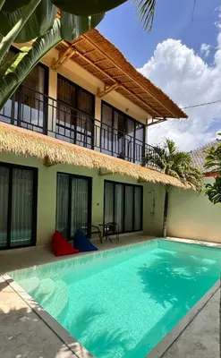 a villa with a swimming pool in front of a house at Villa de Mer Bali in Legian