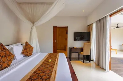 a bedroom with a bed and a desk and a television at The Light Exclusive Villas and SPA in Seminyak