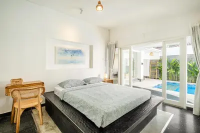 a bedroom with a bed and a desk and a window at LaLeBay Villa Seminyak in Seminyak
