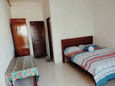 a bedroom with two beds and a bench in it at Bali Holiday Guesthouse near IALF & Benoa in Pesanggaran