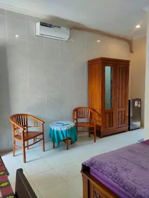 a room with two chairs and a table and a cabinet at Bali Holiday Guesthouse near IALF & Benoa in Pesanggaran