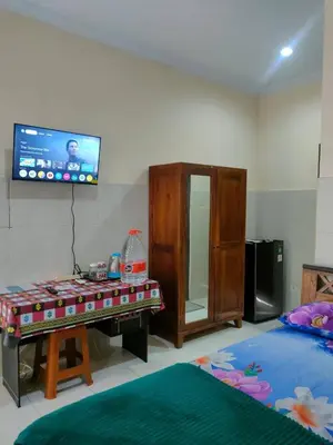 a bedroom with a tv on the wall and a table at Bali Holiday Guesthouse near IALF & Benoa in Pesanggaran
