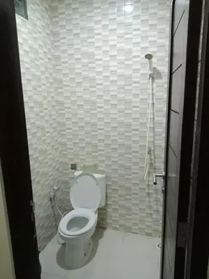 a bathroom with a white toilet in a stall at Bali Holiday Guesthouse near IALF & Benoa in Pesanggaran