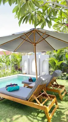 two lounge chairs and an umbrella next to a pool at 2 bedroom villa in Umalas in Kerobokan