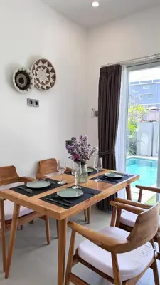 a dining room with a wooden table and a window at 2 bedroom villa in Umalas in Kerobokan