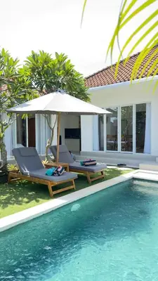 a pool with two chairs and an umbrella next to a house at 2 bedroom villa in Umalas in Kerobokan
