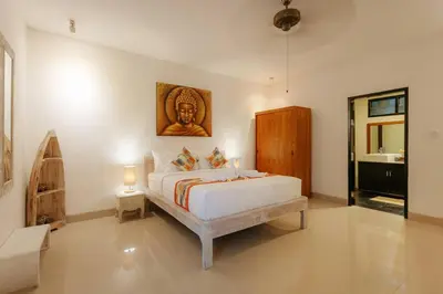 a bedroom with a bed with a picture on the wall at Villa Sri, Seminyak - 3 Bedroom Stylish Pool Villa! in Seminyak