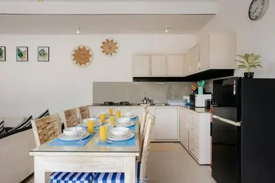 a kitchen with a table with chairs and a black refrigerator at Villa Sri, Seminyak - 3 Bedroom Stylish Pool Villa! in Seminyak