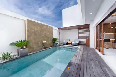 an indoor pool in a house with a wooden deck at Villa Marili Seminyak by Nagisa Bali in Seminyak