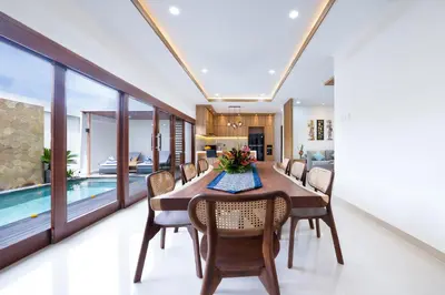 a dining room with a table and chairs and a pool at Villa Marili Seminyak by Nagisa Bali in Seminyak