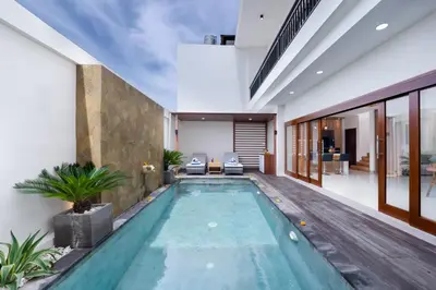 an indoor pool in a house with two chairs at Villa Marili Seminyak by Nagisa Bali in Seminyak