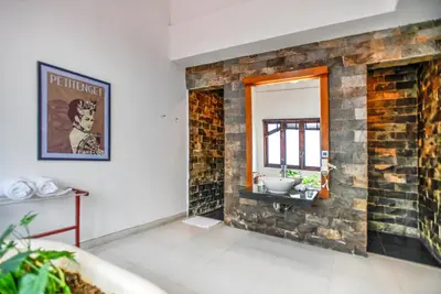 a bathroom with a stone wall with a sink and a mirror at Melo Suites Hotel in Seminyak