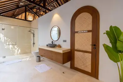 a bathroom with a sink and a wooden door at Green Jimbaran Bay Villa II in Jimbaran