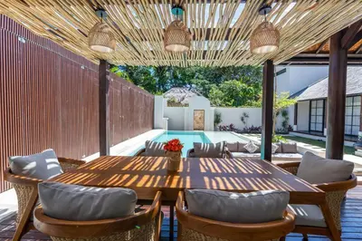 an outdoor patio with a wooden table and chairs at Green Jimbaran Bay Villa II in Jimbaran