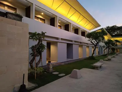 a building with a courtyard with palm trees and benches at Kuta Living by Kamara in Kuta