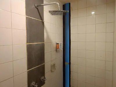 a shower in a bathroom with a blue pole at Kuta Living by Kamara in Kuta