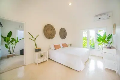 a white bedroom with a large bed and a window at W villa in Seminyak