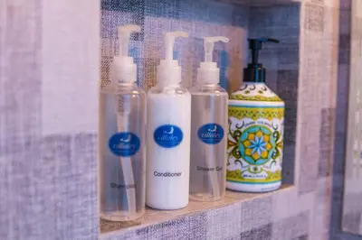 four glass bottles on a shelf in a bathroom at Villa Ley Charming 2 Bedroom Villa Seminyak Private Pool in Seminyak