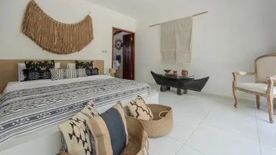 a bedroom with a large bed and a chair at Villa Arev in Kerobokan