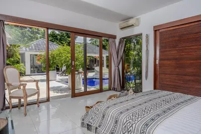 a bedroom with a bed and a view of a pool at Villa Arev in Kerobokan