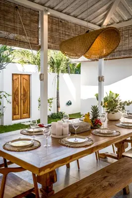 a dining room with a wooden table with wine glasses at Villa Passion by Alfred in Bali in Seminyak