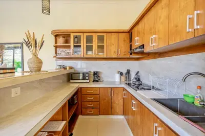 a kitchen with wooden cabinets and a sink at Villa Kumaru Luxury 4BR inc breakfast and airport pickup in Canggu