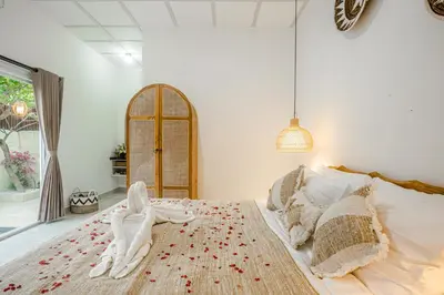 a bedroom with a large bed with two people on it at Villa Jasmine by JB VIllas in Seminyak