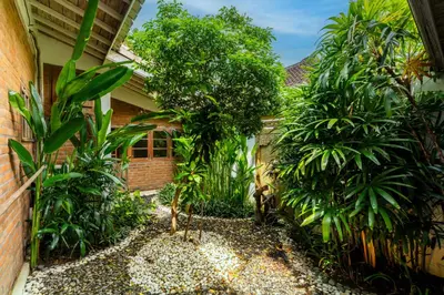 a garden in front of a house with trees at Villa Amsa by Pertama Management in Seminyak