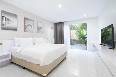 a white bedroom with a large bed and a tv at Cozy Stay Bali by ARM Hospitality in Seminyak