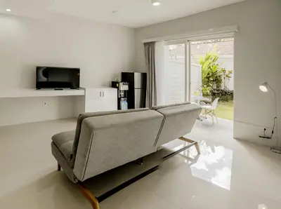 a living room with a couch and a television at Cozy Stay Bali by ARM Hospitality in Seminyak