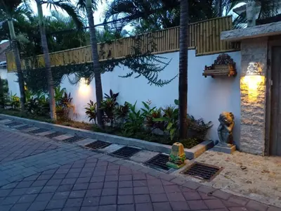 a house with a fence and a statue in front of it at Balinese Luxury in The Centre of Seminyak in Legian